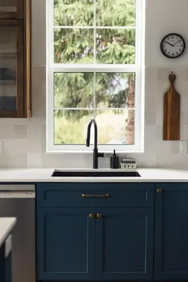 a blue kitchen with a sink and a window at Lokis Loft and Cellar at the 1896 Building in Kaslo