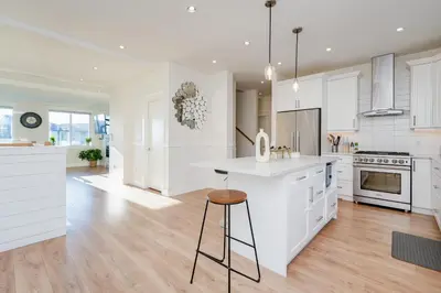 a kitchen with white cabinets and a bar stool at Elegant Home In Victoria,BC in Langford
