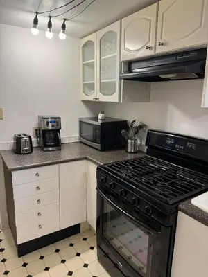 a kitchen with white cabinets and a stove top oven at Bright Garden Suite Across From Park in Kitsilano in Vancouver