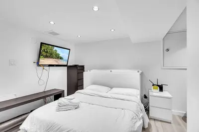 a white bedroom with a bed and a flat screen tv at Comfortable 2-Bed Suite Near UBC in Vancouver