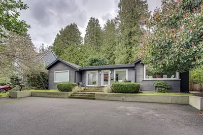 a gray house with a car parked in the driveway at Comfortable 2-Bed Suite Near UBC in Vancouver