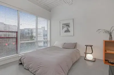 a white bedroom with a bed and a window at Modern and Specious Condo right off Main St in Vancouver