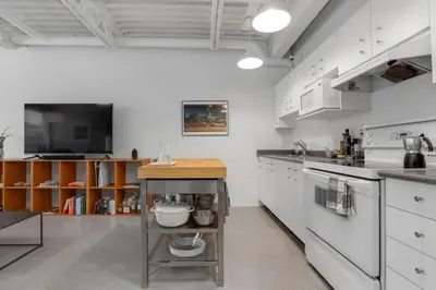 a kitchen with white cabinets and a table in it at Modern and Specious Condo right off Main St in Vancouver