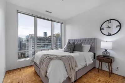 a bedroom with a bed and a clock on the wall at Central Downtown Highrise Condo in Vancouver