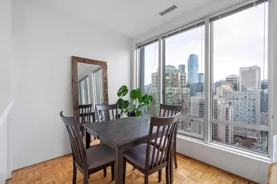 a dining room with a table and chairs and a large window at Central Downtown Highrise Condo in Vancouver