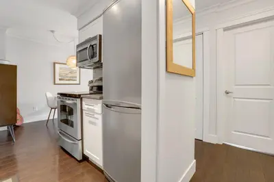 a kitchen with white cabinets and a refrigerator at Modern Kitsilano 1 bedroom steps from the Beach in Vancouver