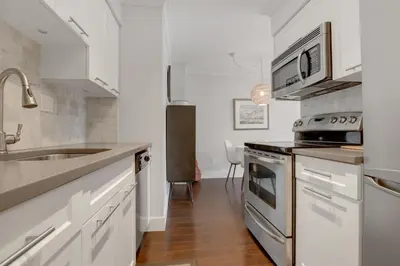 a white kitchen with a sink and a stove at Modern Kitsilano 1 bedroom steps from the Beach in Vancouver