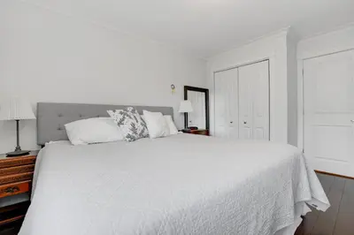 a white bedroom with a white bed and a window at Modern Kitsilano 1 bedroom steps from the Beach in Vancouver