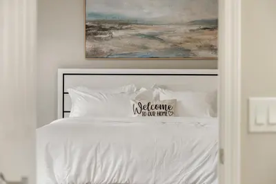a bedroom with a white bed with a painting at A beautiful home in Airdrie in Airdrie