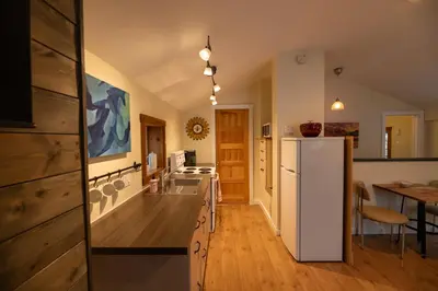 a kitchen with a white refrigerator and a table at Located in Downtown Whitehorse - Treehouse in Whitehorse
