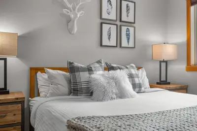 a bedroom with a bed with white sheets and pillows at Modern Cabin Vibes with pool at The Lodges in Canmore