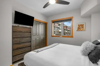 a bedroom with a bed and a flat screen tv at Modern Cabin Vibes with pool at The Lodges in Canmore