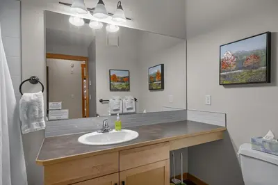 a bathroom with a sink and a large mirror at Modern Cabin Vibes with pool at The Lodges in Canmore