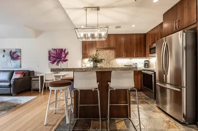 a kitchen with a stainless steel refrigerator and bar stools at Stunning Silver Creek 1Br Mtn view penthouse in Canmore