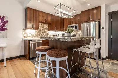 a kitchen with wooden cabinets and bar stools at Stunning Silver Creek 1Br Mtn view penthouse in Canmore