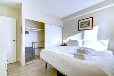 a bedroom with a white bed with towels on it at Spacious Top Floor at Stampede w Free Parking and AC in Calgary