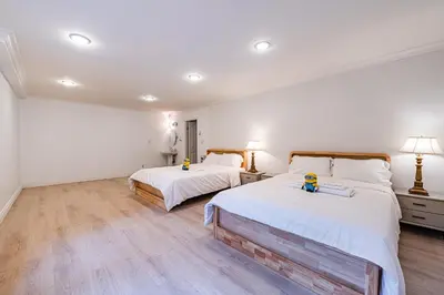 two beds in a room with white walls and wooden floors at The Ester House in Vancouver