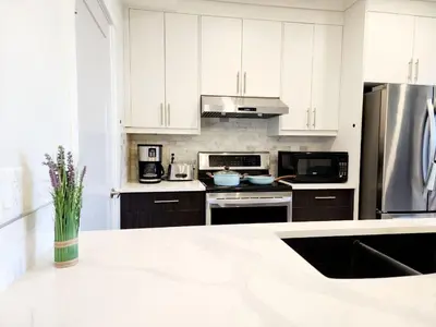 a kitchen with white cabinets and a stainless steel refrigerator at Luxury Cozy Basement Suite in Leduc