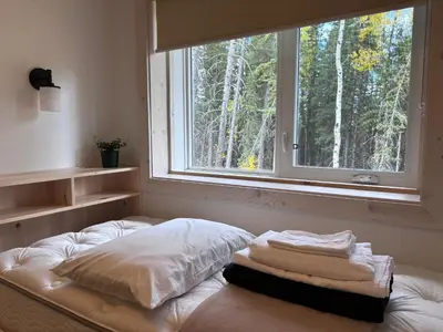 a pile of towels sitting on a bed in front of a window at Jasper East Hostel - Near Jasper National Park East Gate Entrance in Jasper