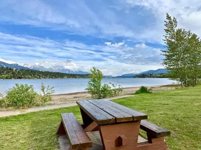a wooden bench sitting on the grass near a lake at Lake View From Every Window! in Invermere