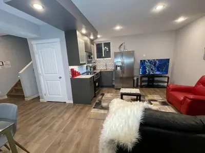 a living room with a red couch and a kitchen at Comfortable and Beautiful Brand-New Suite BSMT-Two Bedroom, Two Washrooms in Calgary