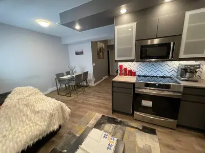 a kitchen with a stove top oven next to a table at Comfortable and Beautiful Brand-New Suite BSMT-Two Bedroom, Two Washrooms in Calgary