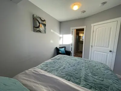 a bedroom with a bed and a chair at Comfortable and Beautiful Brand-New Suite BSMT-Two Bedroom, Two Washrooms in Calgary