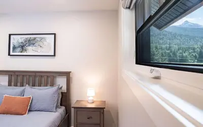 a bedroom with a bed and a large window at The Cedar Suite - Secluded Mountain Retreat with Forest Views and Hot Tub in Revelstoke