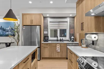 a kitchen with wooden cabinets and a refrigerator at Sisters Summit Villa by WeekAway Vacations in Canmore