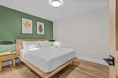 a bedroom with a white bed and a green wall at Sisters Summit Villa by WeekAway Vacations in Canmore