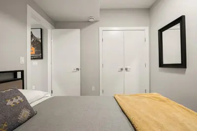 a white bedroom with a bed and a mirror at Heart of Hillhurst 1BR Home ! in Calgary