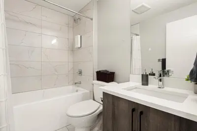 a white bathroom with a toilet and a sink at Heart of Hillhurst 1BR Home ! in Calgary