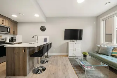 a kitchen and living room with a counter and a couch at Heart of Hillhurst 1BR Home ! in Calgary