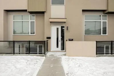 a house with a white door in the snow at Heart of Hillhurst 1BR Home ! in Calgary