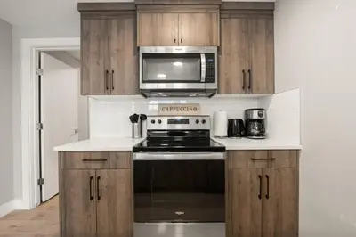 a kitchen with a stove and a microwave at Heart of Hillhurst 1BR Home ! in Calgary