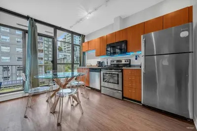 a kitchen with a table and a stainless steel refrigerator at Lovely 2-Bedrooms Downtown suite Free Parking in Vancouver