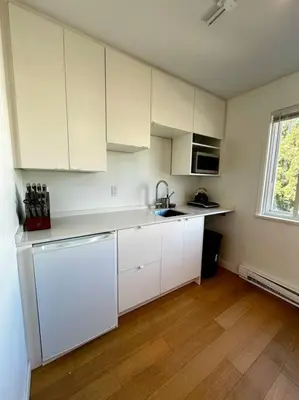 a kitchen with white cabinets and a wooden floor at Charming East Van Home Near DT and Commercial St in Vancouver