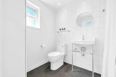 a white bathroom with a toilet and a sink at Charming East Van Home Near DT and Commercial St in Vancouver