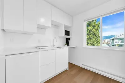 a kitchen with white cabinets and a large window at Charming East Van Home Near DT and Commercial St in Vancouver