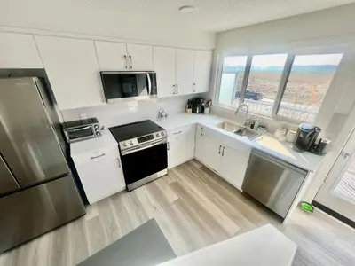 a kitchen with white cabinets and a stainless steel refrigerator at Humble Living in Edmonton