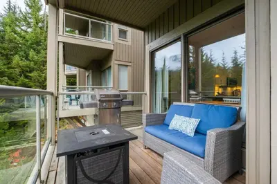 a screened in porch with a blue couch and a table at Blueberry Hill Estates 3180 by Outpost Whistler in Whistler