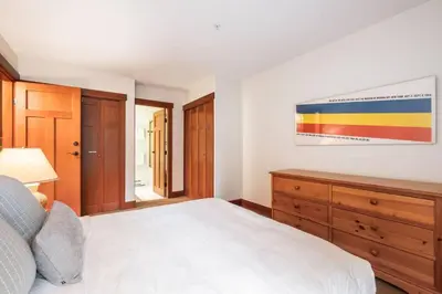 a bedroom with a white bed and a wooden dresser at Blueberry Hill Estates 3180 by Outpost Whistler in Whistler