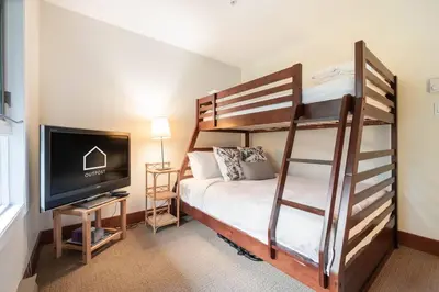 a bedroom with a bunk bed and a flat screen tv at Blueberry Hill Estates 3180 by Outpost Whistler in Whistler