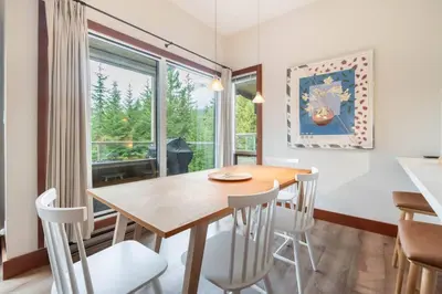 a dining room with a table and chairs and a window at Blueberry Hill Estates 3180 by Outpost Whistler in Whistler