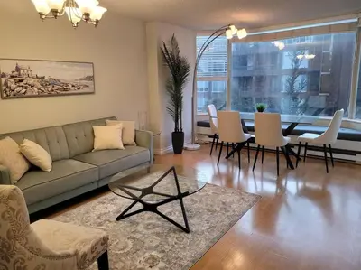a living room with a couch and a table and chairs at Beautiful 2 Beds Dwtn apt Free Parking King Bed in Vancouver