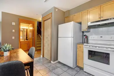 a kitchen with a white refrigerator and a table at Cozy Condo with Epic Mountain Views, Parking, Air Con in Canmore