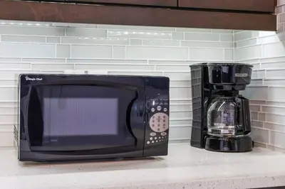 a microwave sitting on a counter next to a coffee maker at Bright & Cozy 2-Bedroom Basement Suite in Chestermere
