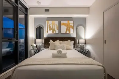 a bedroom with a large white bed with two tables at Poolside Bliss - 22 FL w Tower Views! FREE Banff Pass, Gym, Parking, Summer Outdoor Pool! in Calgary