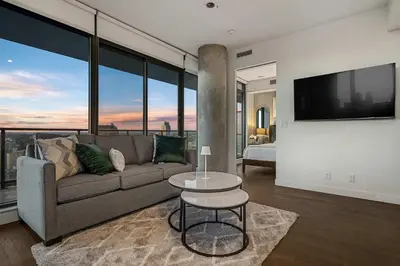 a living room with a couch and a flat screen tv at Poolside Bliss - 22 FL w Tower Views! FREE Banff Pass, Gym, Parking, Summer Outdoor Pool! in Calgary