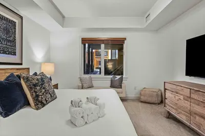 a bedroom with a bed and a flat screen tv at Spacious 2bed with Hot Tub in Canmore